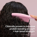 Person combing wet hair with a pink comb against a light purple background
