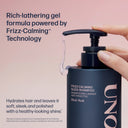 Shampoo bottle with pump being held, featuring text about frizz-calming technology on a pink background.