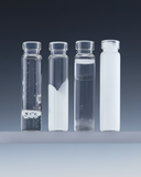 Four transparent glass vials containing different hair care formula textures, ranging from clear to milky, displayed on a clean studio surface against a dark gradient background