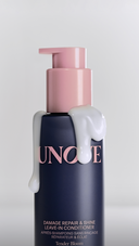 UNOVE Damage Repair & Shine leave-in conditioner bottle with creamy texture dripping over the pump, displayed against a clean studio background